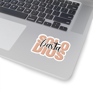 Puede incluir: Una pegatina de color melocotón con el texto "Solo basta Dios" en letras negras. El texto está estilizado con una cruz sobre la palabra "basta".