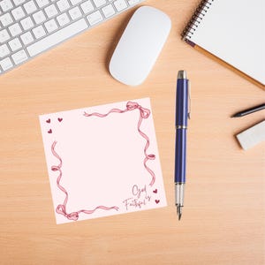 May include: A pink notepad with a pink ribbon border and the text "God is Faithful" in cursive. There are small pink hearts around the border.