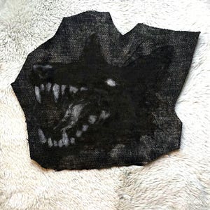 May include: Black and white denim patch with a snarling wolf's head design.