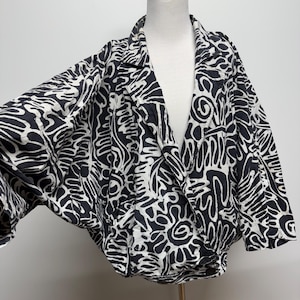 May include: Black and white patterned blazer with a unique abstract design. The jacket is displayed on a mannequin, showcasing its oversized fit and distinctive pattern. The blazer features a classic lapel and button closure.