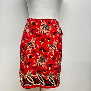 May include: A red wrap skirt with a floral print and a black and white paisley border.