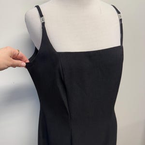 May include: A black sleeveless dress with a square neckline and a fitted silhouette. The straps have small rhinestone embellishments.