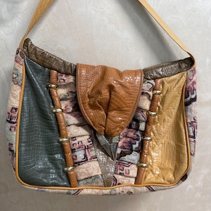 May include: A shoulder bag with a patchwork design. The bag features a variety of textures and colours, including tan, brown, green, and yellow leather and fabric. The bag has a long, tan strap and a flap closure.