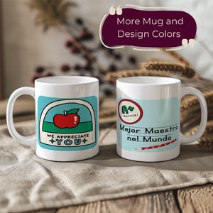 Peut inclure: Deux tasses en céramique blanche avec des motifs colorés. La tasse de gauche a une pomme rouge et le texte "We appreciate you". La tasse de droite a un motif bleu et rouge avec le texte "Mejor Maestro nel Mundo".