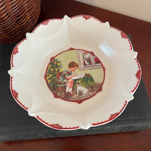 May include: White ceramic bowl with a red rim and a scalloped edge. The bowl features a vintage Christmas scene with a girl writing a letter to Santa Claus, a decorated Christmas tree, and a dog.