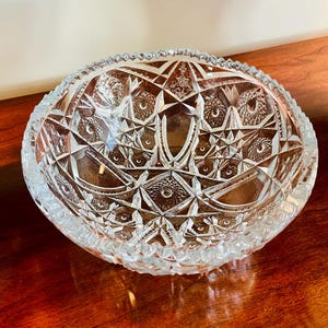 May include: A clear glass bowl with a cut glass design. The bowl has a scalloped edge and a round base.