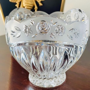 May include: A clear glass bowl with a frosted rim and etched floral designs. The bowl has a scalloped edge and a pedestal base.