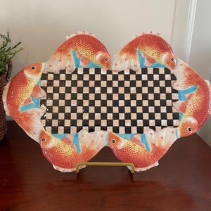 May include: A ceramic serving tray with a black and white checkered design and a border of orange and red fish.