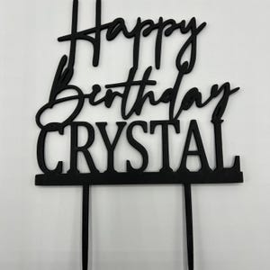 Könnte beinhalten: Schwarzer Acryl-Kuchentopper mit dem Text "Happy Birthday Crystal" in einer modernen Schreibschrift.