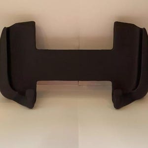 Peut inclure: Support de t&eacute;l&eacute;phone en plastique noir avec deux bras incurv&eacute;s et une base plate.