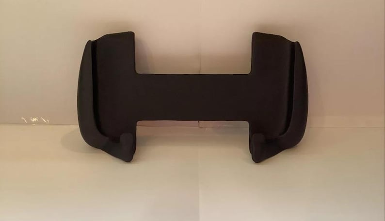 Peut inclure: Support de t&eacute;l&eacute;phone en plastique noir avec deux bras incurv&eacute;s et une base plate.