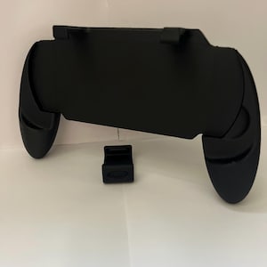 Może przedstawiać: Czarny plastikowy kontroler do gier mobilnych z dwoma odłączanymi uchwytami. Kontroler jest zaprojektowany do dopasowania do smartfona.