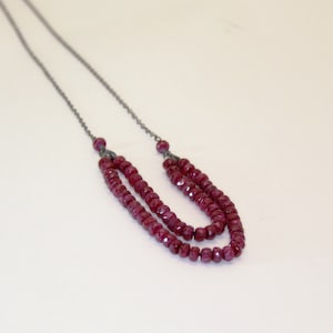 May include: A silver chain necklace with two strands of dark red ruby beads.