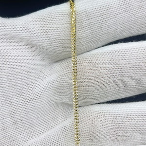 May include: A fine gold chain necklace with a textured design. The chain is shown against a white fabric background, accentuating its intricate details and golden colour. This necklace is suitable for everyday wear or special occasions.