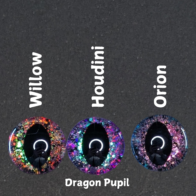 Puede incluir: Tres ojos redondos de resina, iridiscentes y llenos de purpurina, con pupilas negras. Los ojos est&aacute;n etiquetados como "Willow", "Houdini" y "Orion". El texto "Dragon Pupil" est&aacute; debajo de los ojos.