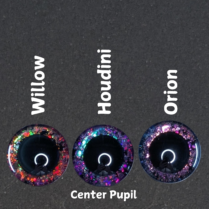 Puede incluir: Tres ojos redondos de vidrio con pupilas negras y detalles de purpurina de colores. Los ojos est&aacute;n etiquetados como "Willow", "Houdini" y "Orion". El texto "Center Pupil" est&aacute; debajo de los ojos.