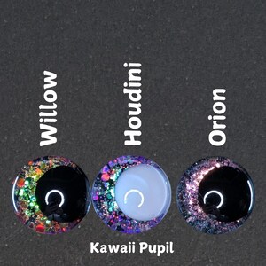 Puede incluir: Tres ojos redondos, negros y blancos, de resina, llenos de purpurina, kawaii con una pupila en forma de media luna. Los ojos est&aacute;n etiquetados como "Willow", "Houdini" y "Orion".