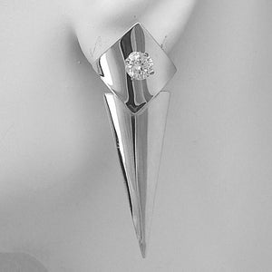 May include: A silver earring with a diamond set in a square top and a long, pointed bottom. The earring is shown on a white background, highlighting its modern design and reflective surface.