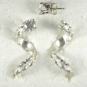 May include: A pair of silver earrings with a spiral design and a clear, round gemstone at the top. The earrings have a post-back closure. The design includes a leaf pattern along the spiral.