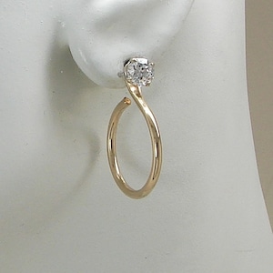 May include: Gold hoop earrings with a single clear cubic zirconia stone.