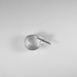 May include: A single silver hoop earring with a post and butterfly clasp. The earring is a half-circle shape, with a textured edge. The earring is set against a white background.