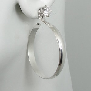 May include: Silver hoop earrings with a clear cubic zirconia stone on the top of the hoop.