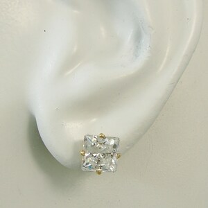 May include: A pair of gold stud earrings with a clear square-shaped gemstone.