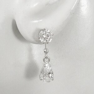 May include: Silver dangle earrings with a round clear stone at the top and a pear-shaped clear stone at the bottom.