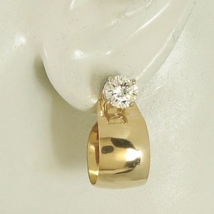 May include: Gold earring with a round, clear gemstone.