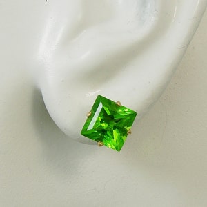 May include: A pair of gold earrings with square green gemstones.