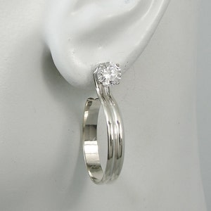 May include: Silver hoop earrings with a single clear cubic zirconia stone.