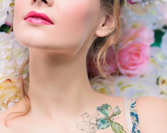 May include: A woman with a flower crown has a temporary tattoo of a green and white flower on her shoulder.