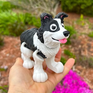 May include: A black and white toy dog with a pink tongue sticking out. The dog has a jointed body and is posed in a walking position.