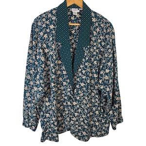May include: A teal floral print blazer with a contrasting dark green collar featuring white polka dots. The blazer has long sleeves and a relaxed fit, perfect for layering. The floral pattern includes small, cream-colored flowers.