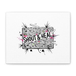 May include: A canvas print with a black and white doodle design of an open book. The words "SHOUT & HEAL" are in bold letters. The design includes splashes of pink and green paint, and several pens.
