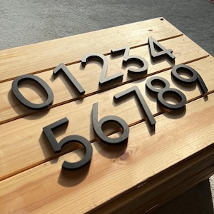 Peut inclure: Nombres noirs de 0 à 9 sur une surface en bois. Les chiffres sont faits d'un matériau épais et durable et sont parfaits pour ajouter une touche moderne à n'importe quelle maison.