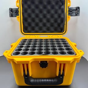 May include: A bright yellow, open hard case with a black handle and latches. The interior has black foam inserts with multiple circular cutouts. The case is designed to protect and organise items.