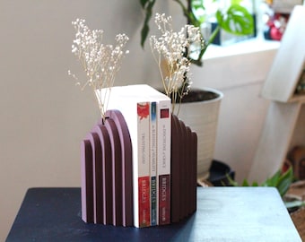 May include: A pair of purple bookends with a geometric design, holding up three books. The books are titled "Bridges", "Trusting God", and "Discipline + Grace: A Blessing + Humility".