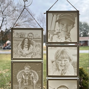 May include: A set of five sepia-toned photographs of different people, displayed in a vertical row on a window. The photos are held in place by suction cups and string.
