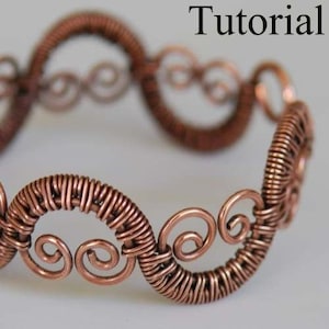 May include: A copper wire bracelet with a woven design and intricate swirls. The bracelet is made of multiple loops of wire that are connected together to form a continuous band.