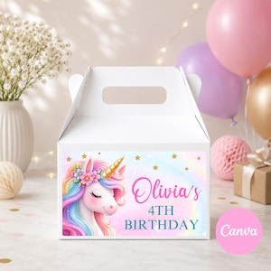 May include: White party favor box with a unicorn design. The box features a colorful unicorn with a gold horn, a floral crown, and the text "Olivia's 4th Birthday". Balloons and other party decorations are in the background.