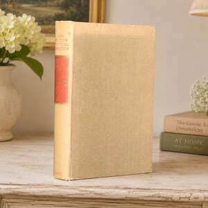 May include: A hardcover book with a light beige fabric cover and a red spine label. The spine features the text The British Political Tradition in white lettering. The book stands upright, displaying its textured surface and rectangular shape.