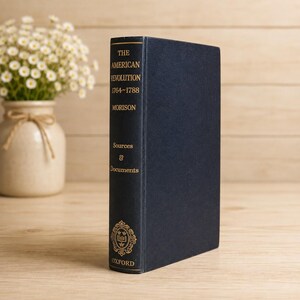 May include: A dark blue hardcover book titled The American Revolution 1764-1788 by Morison, featuring the subtitle Sources & Documents and an Oxford emblem in gold lettering on the spine, standing upright with a clean, solid-colored cover.