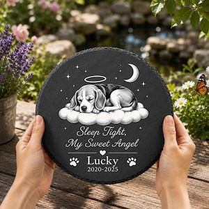 Könnte beinhalten: Eine runde Gedenktafel aus schwarzem Schiefer mit einer Gravur eines schlafenden Beagles auf einer Wolke unter einer Mondsichel und einem Heiligenschein. Der Text lautet: Sleep Tight, My Sweet Angel, Lucky, sowie die Jahre 2020-2025 mit Pfotenabdrücken.