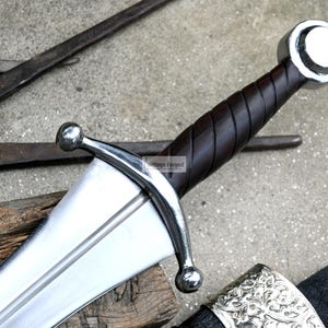 May include: A silver sword with a brown leather wrapped handle and a silver pommel. The sword has a double-edged blade and a crossguard with two rounded ends.