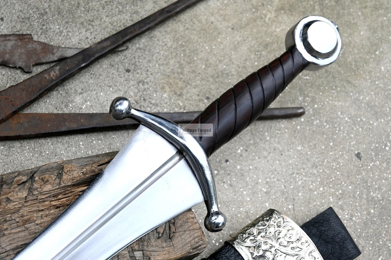 May include: A silver sword with a brown leather wrapped handle and a silver pommel. The sword has a double-edged blade and a crossguard with two rounded ends.
