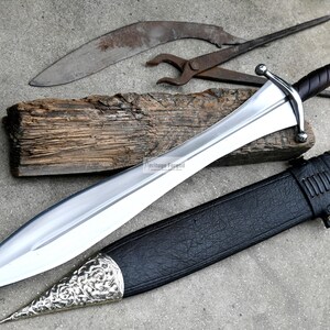 May include: A silver sword with a black leather scabbard and a silver pommel. The sword has a long, straight blade and a crossguard. The scabbard has a silver tip and a silver band around the middle.