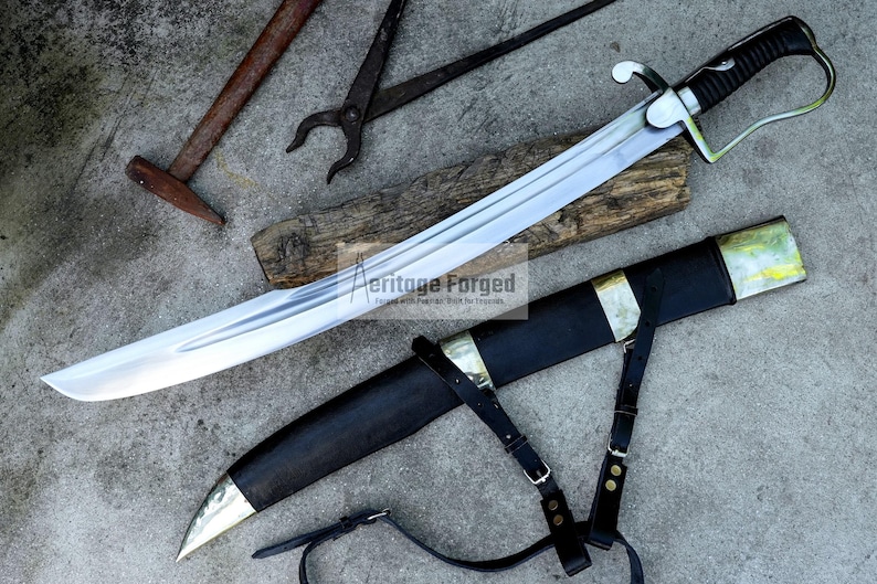 May include: A large, curved sword with a silver blade and black handle, resting on a wooden plank. The sword is accompanied by a black sheath with gold accents and leather straps. Other tools are in the background.