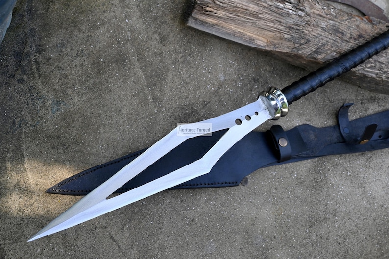 Puede incluir: Una espada plateada con mango negro y una vaina de cuero. La espada tiene una hoja larga y puntiaguda con un dise&ntilde;o en forma de diamante. La vaina es de cuero negro con una correa de cuero marr&oacute;n.