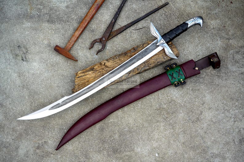 May include: A handcrafted sword with a silver blade and black handle, resting on a wooden plank. A burgundy leather sheath with green accents and a hammer and pliers are also visible, suggesting a blacksmithing theme.